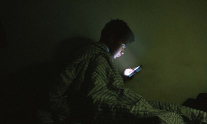 A man is scrolling the phone at bed time